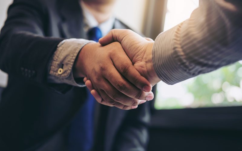 Two business men shaking hands during a meeting to sign agreement and become a business partner, enterprises, companies, confident, success dealing, contract between their firms.